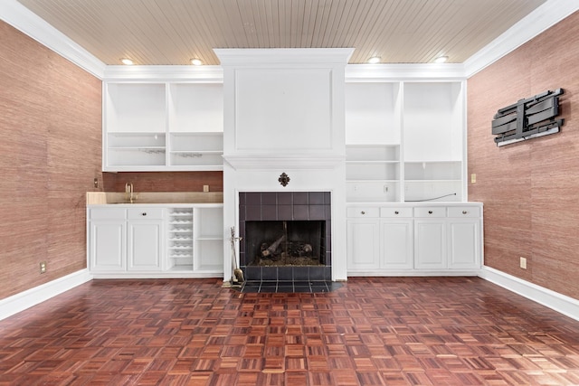 unfurnished living room with built in shelves, baseboards, wood ceiling, and ornamental molding