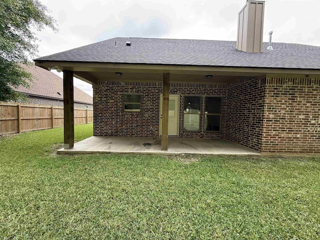 7735 Windcastle Dr, Beaumont, TX 77713 - rear view of house with brick siding, a patio, roof with shingles, and a chimney