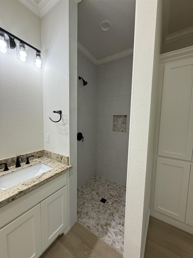 7735 Windcastle Dr, Beaumont, TX 77713 - bathroom featuring ornamental molding, tiled shower, wood finished floors, vanity, and a textured wall