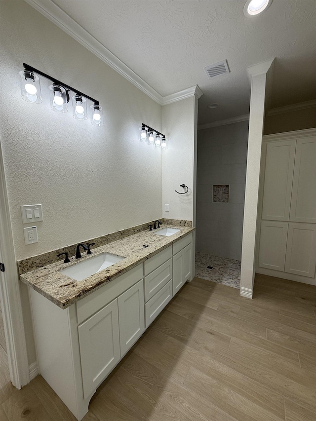 7735 Windcastle Dr, Beaumont, TX 77713 - full bathroom featuring crown molding, a tile shower, double vanity, wood finished floors, and a textured ceiling