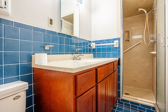 bathroom featuring a shower with door, tile walls, vanity, tile patterned floors, and toilet