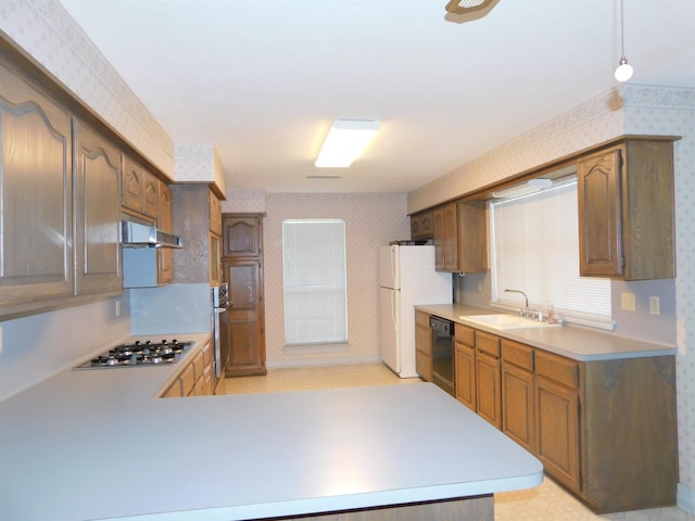 6340 Capitol St, Groves, TX 77619 - kitchen with appliances with stainless steel finishes, wallpapered walls, under cabinet range hood, light countertops, and a peninsula