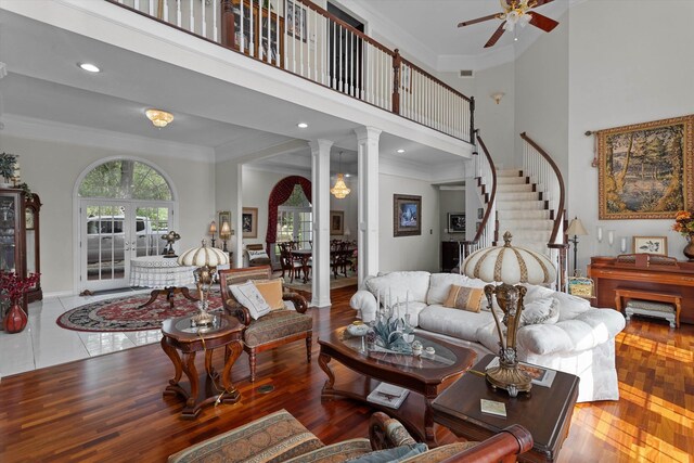 living room with french doors, ceiling fan, ornate columns, a towering ceiling, and ornamental molding