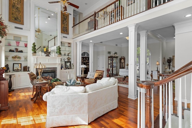 living room with a fireplace, a towering ceiling, and wood-type flooring