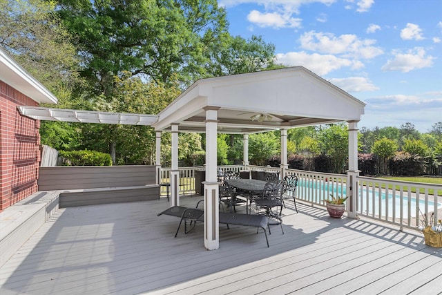 wooden terrace with a gazebo, ceiling fan, and a fenced in pool