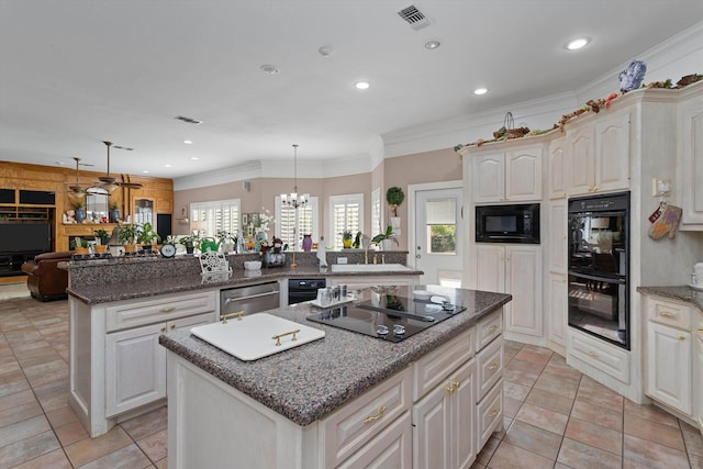 kitchen featuring black appliances, decorative light fixtures, a center island, and ornamental molding