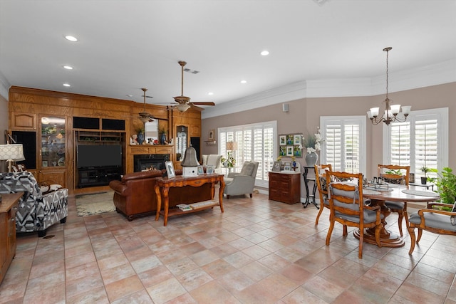 living room featuring built in shelves, ceiling fan with notable chandelier, plenty of natural light, and ornamental molding