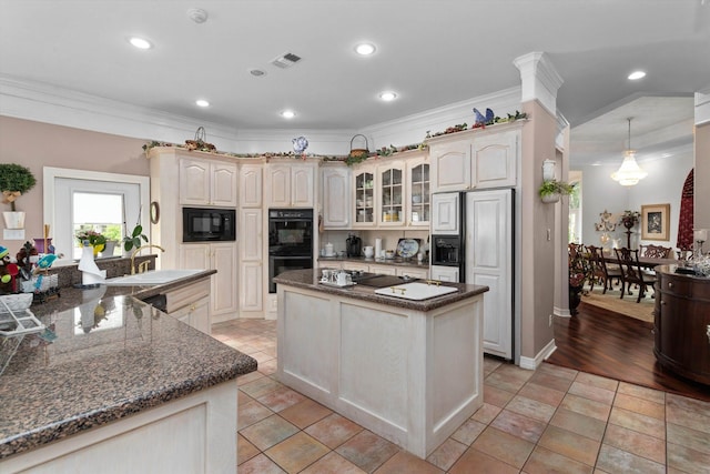 kitchen featuring crown molding, pendant lighting, cream cabinetry, a kitchen island, and black appliances