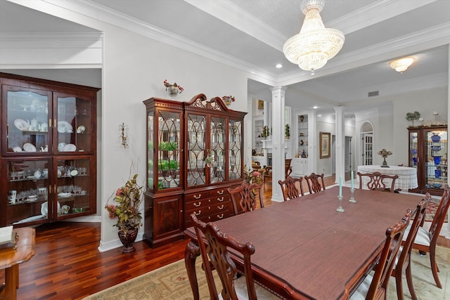 dining room with decorative columns, dark wood-type flooring, ornamental molding, and a notable chandelier