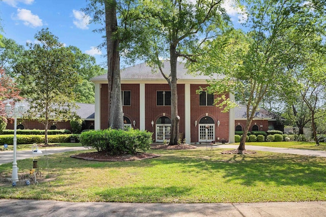 neoclassical home featuring a front yard and french doors