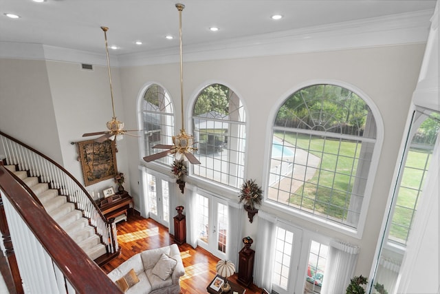 entryway with french doors, ceiling fan, crown molding, wood-type flooring, and a high ceiling