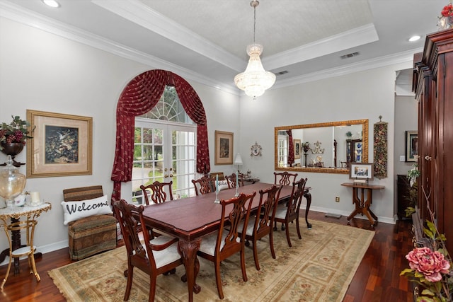 dining space with french doors, a raised ceiling, dark hardwood / wood-style floors, ornamental molding, and a notable chandelier