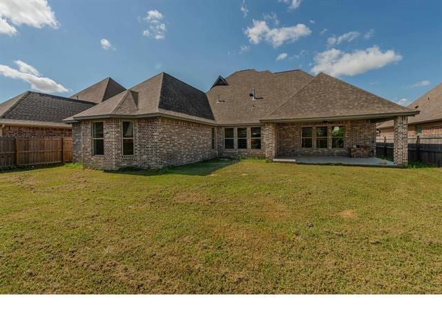 back of property with a lawn, a fenced backyard, brick siding, and a patio