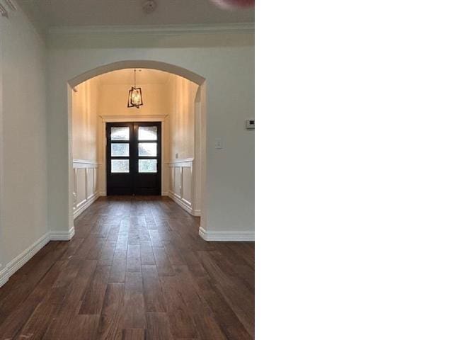 foyer with arched walkways, crown molding, dark wood-style floors, and baseboards