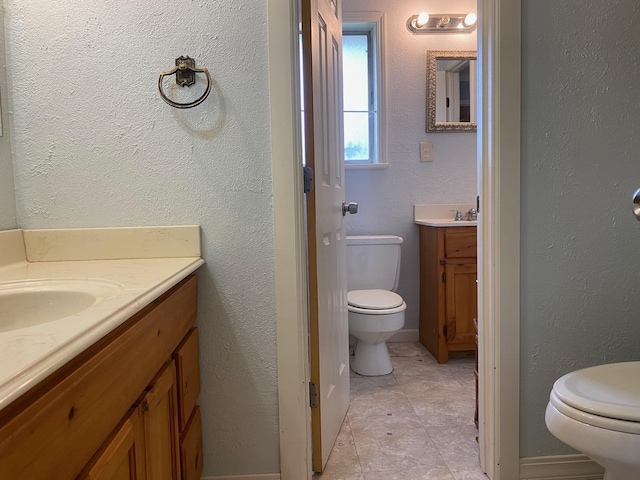 - bathroom with toilet, vanity, and baseboards