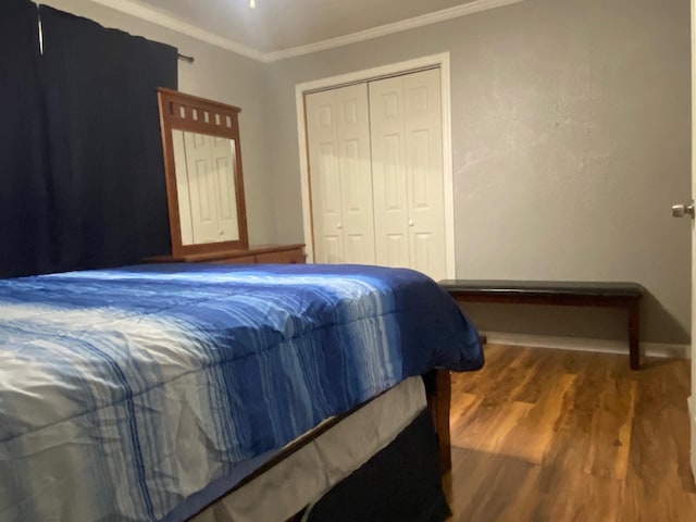  - bedroom with wood finished floors, ornamental molding, a closet, and baseboards