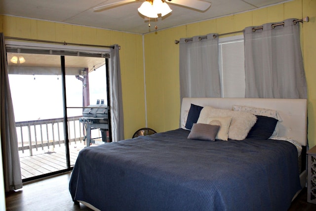 bedroom featuring access to exterior, ceiling fan, wooden walls, and wood-type flooring