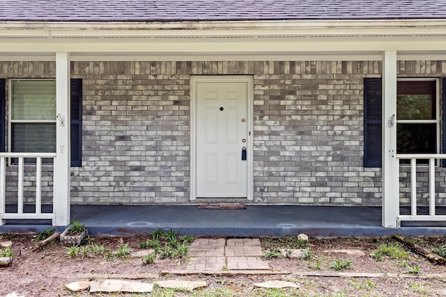 7714 N Linscomb Rd, Vidor, TX 77662 - doorway to property with a porch, roof with shingles, and brick siding