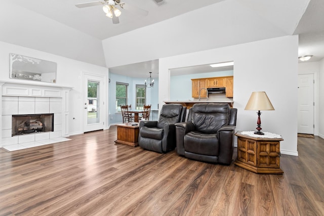 7714 N Linscomb Rd, Vidor, TX 77662 - living room featuring ceiling fan with notable chandelier, baseboards, wood finished floors, lofted ceiling, and a tile fireplace