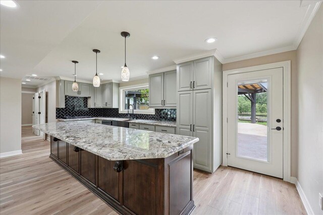 102 Timbercreek Dr, Lumberton, TX 77657 - kitchen featuring decorative backsplash, light wood-style floors, ornamental molding, light stone counters, and a kitchen island