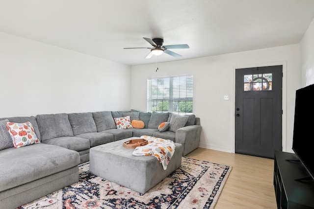 living area featuring light wood-style floors, baseboards, and a ceiling fan