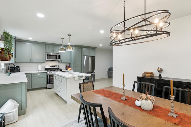 kitchen featuring a center island, stainless steel appliances, light countertops, hanging light fixtures, and a sink