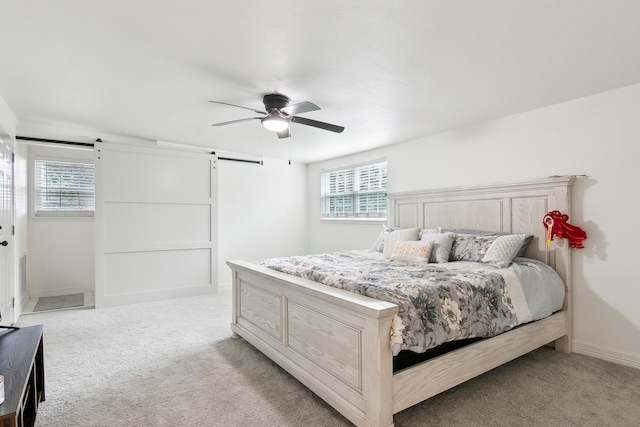 bedroom with a ceiling fan, light colored carpet, baseboards, and a barn door