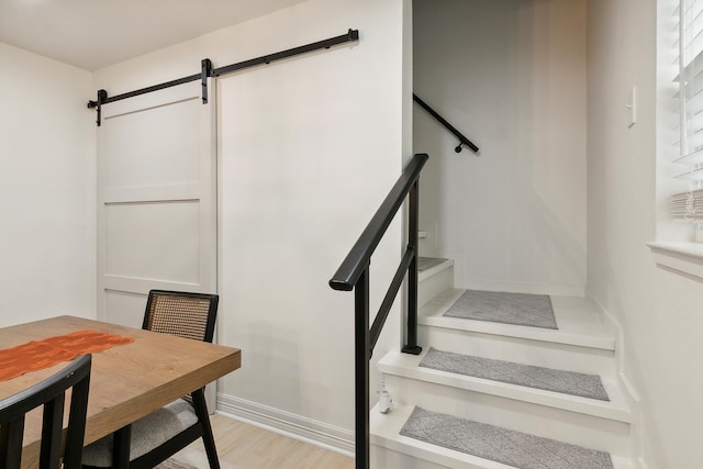 staircase with a barn door and wood finished floors