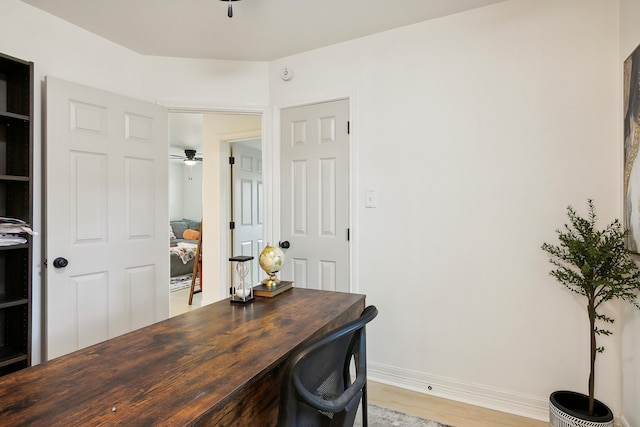 home office with light wood finished floors, ceiling fan, and baseboards