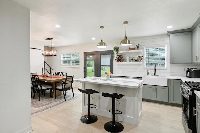 kitchen with light countertops, light wood-type flooring, gas stove, and a sink