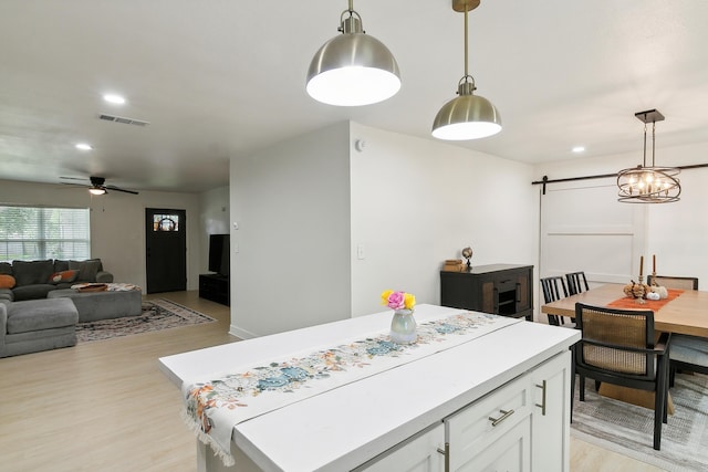 kitchen featuring a barn door, visible vents, white cabinetry, light countertops, and a center island