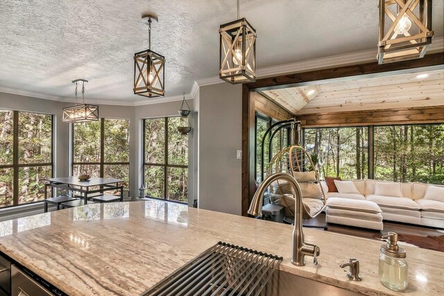 kitchen featuring light stone countertops, ornamental molding, and a textured ceiling