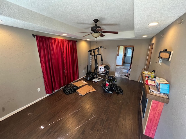 exercise room featuring dark hardwood / wood-style floors, a textured ceiling, and ceiling fan