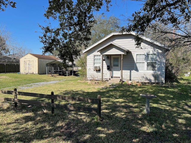 bungalow-style house featuring cooling unit, a carport, a storage shed, and a front yard