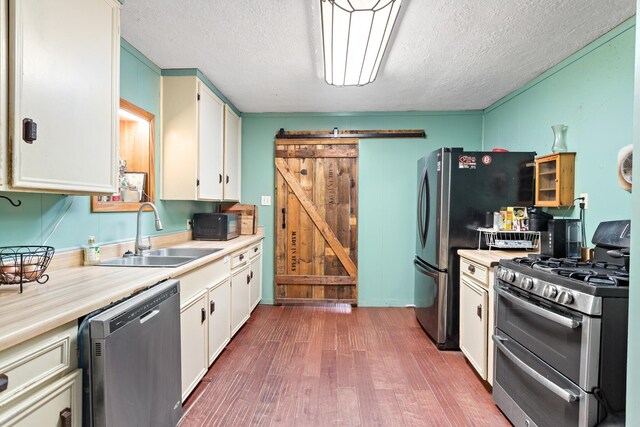 6531 Childress Ln, Kountze, TX 77625 - kitchen with appliances with stainless steel finishes, a sink, dark wood finished floors, light countertops, and a textured ceiling