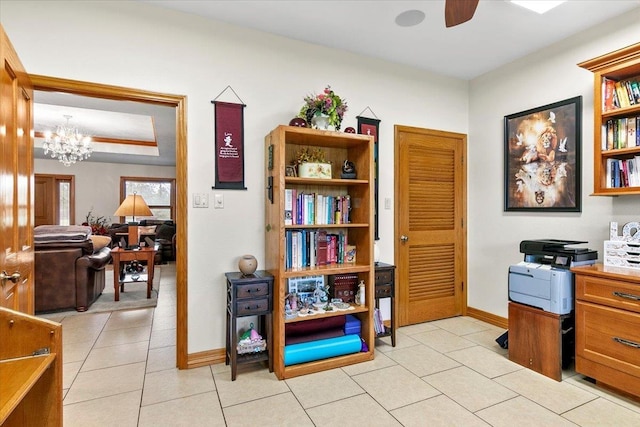 tiled home office featuring ceiling fan with notable chandelier