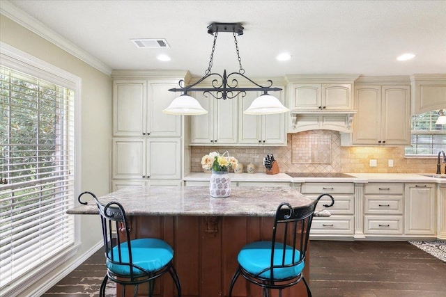 kitchen featuring sink, dark hardwood / wood-style flooring, decorative light fixtures, and cream cabinetry