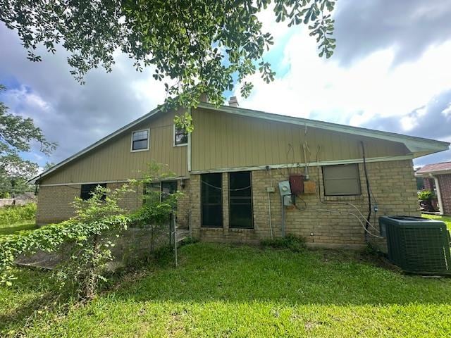5935 Falcon Ln, Beaumont, TX 77708 - rear view of house with central AC, brick siding, and a yard