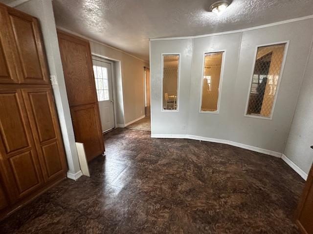 unfurnished room with ornamental molding and a textured ceiling