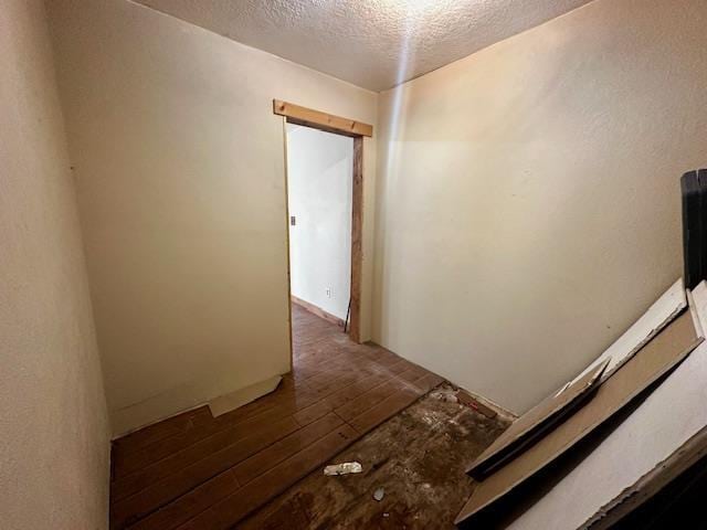 hall featuring dark wood-type flooring and a textured ceiling