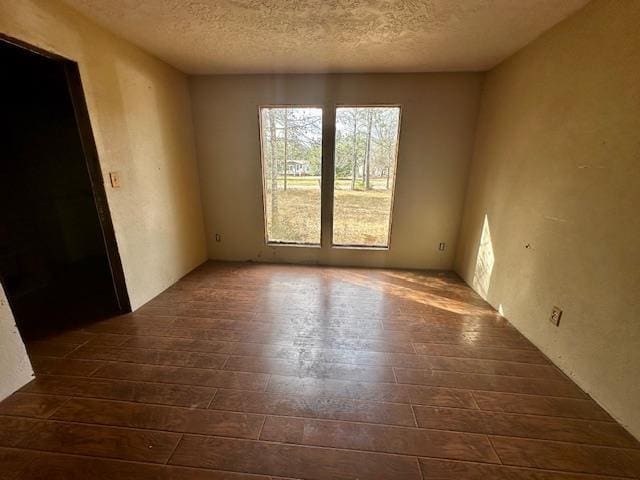 empty room with dark hardwood / wood-style floors and a textured ceiling