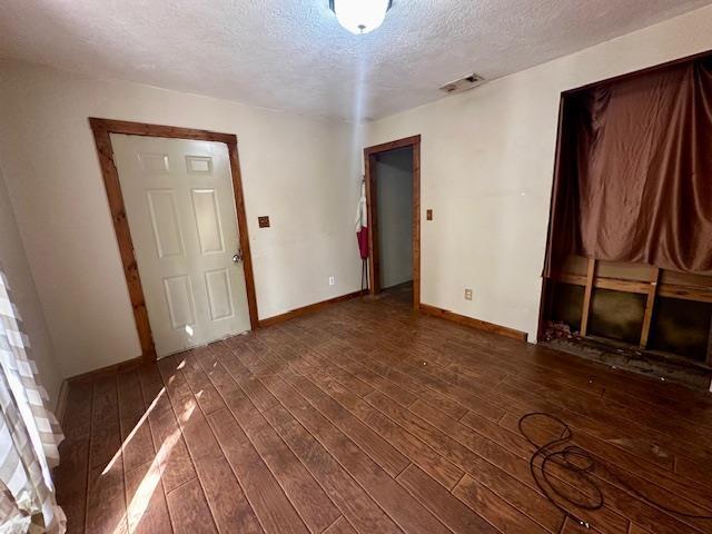 unfurnished room featuring a textured ceiling and dark hardwood / wood-style flooring