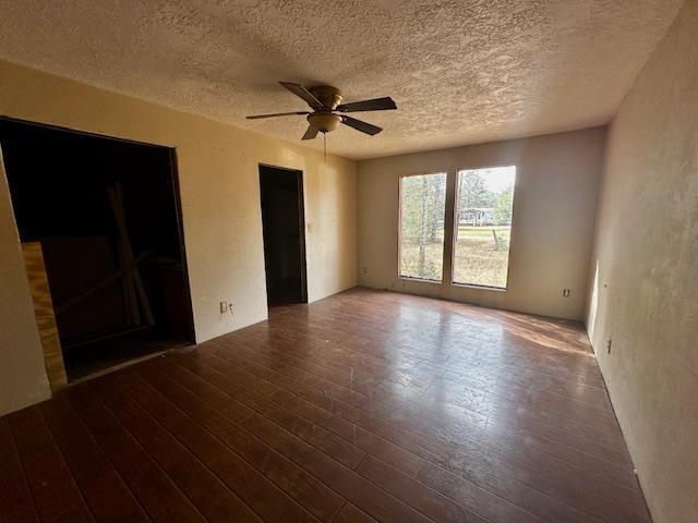 empty room featuring ceiling fan, dark hardwood / wood-style floors, and a textured ceiling