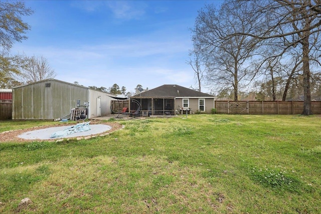 view of yard with a patio, an outdoor structure, a fenced backyard, and a sunroom