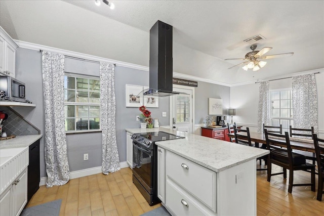 kitchen with visible vents, black electric range, island exhaust hood, a peninsula, and light wood finished floors