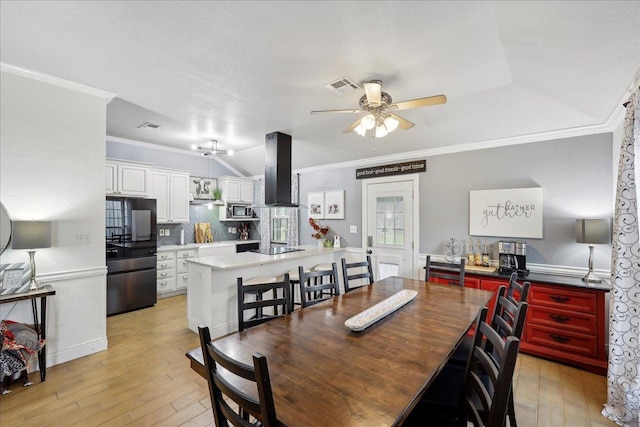 dining room with a ceiling fan, crown molding, light wood-style floors, and visible vents