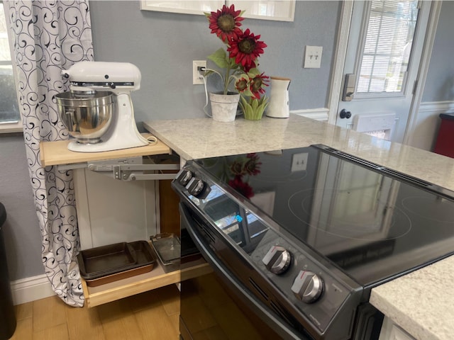 kitchen with light countertops, black / electric stove, and wood finished floors