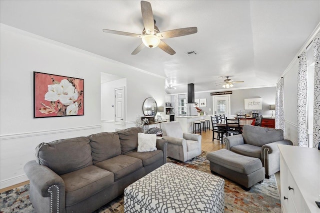 living area with visible vents, light wood-type flooring, ceiling fan, and ornamental molding