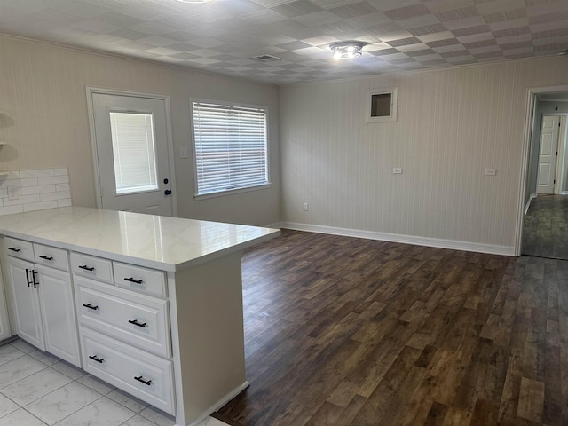 kitchen with a peninsula, baseboards, white cabinetry, light wood-type flooring, and ornamental molding