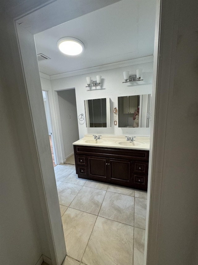 bathroom featuring double vanity, visible vents, ornamental molding, and a sink